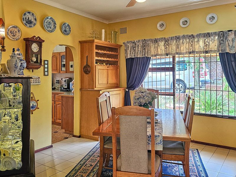 A traditional dining room featuring tiled flooring, a brick fireplace, and an arched doorway leading to the kitchen area.