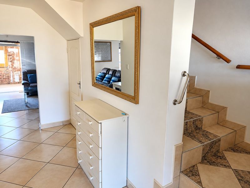 Welcoming entrance hall featuring tiled flooring and a staircase with a wooden handrail and decorative tiled risers.