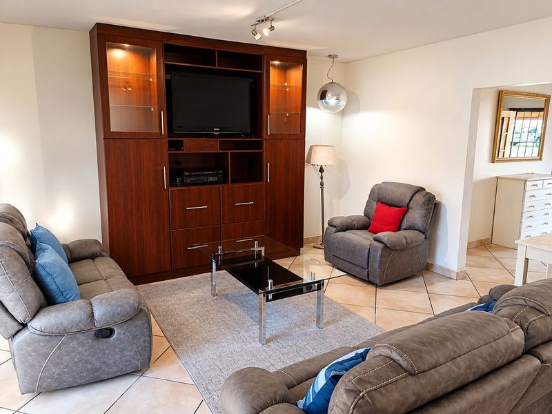 A comfortable living room featuring large built-in wooden cabinetry, ceramic tile flooring, and modern lighting fixtures, creating a functional and inviting space.