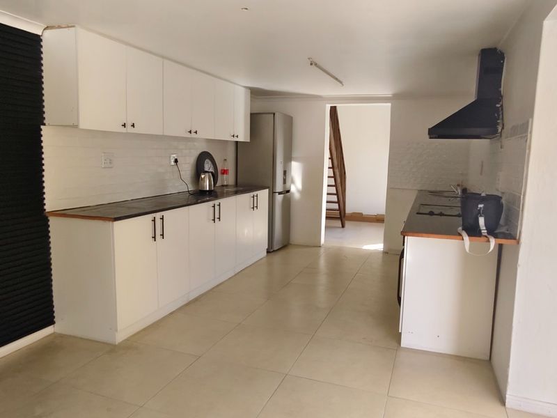 A functional kitchen featuring white cabinetry, dark countertops, and a tiled backsplash, offering a clean and neutral space ready for personalization.