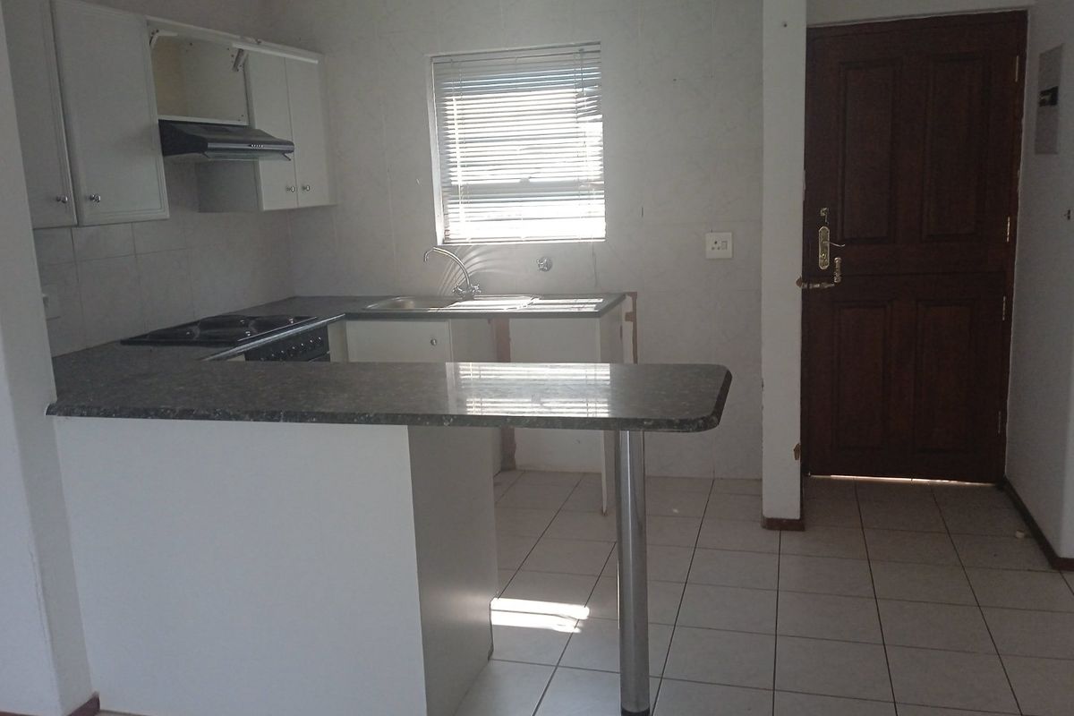 A functional kitchen featuring built-in cabinetry, a breakfast bar, and a built-in hob. The space is currently vacant and ready for updates.
