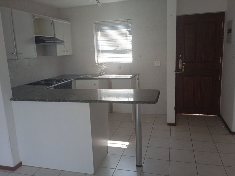 A functional kitchen featuring built-in cabinetry, a breakfast bar, and a built-in hob. The space is currently vacant and ready for updates.