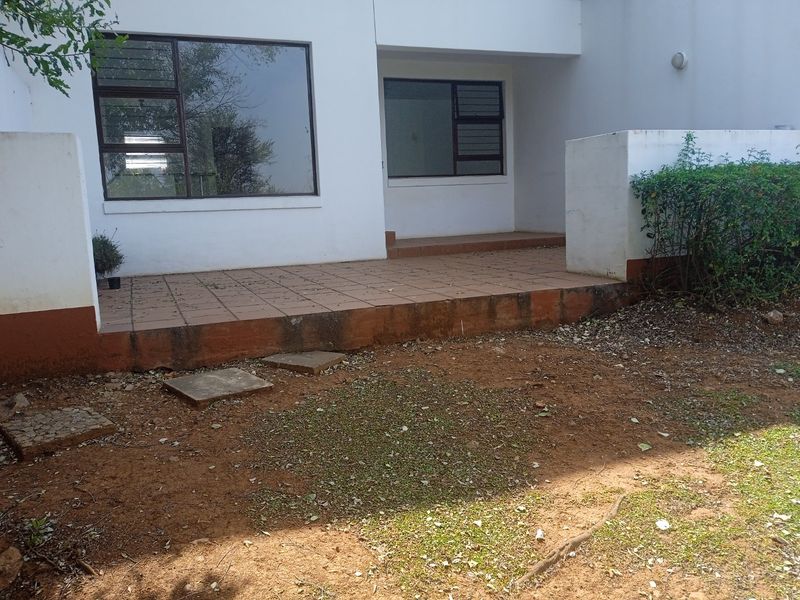Rear exterior view of the apartment featuring a tiled patio area and direct access to the garden space.