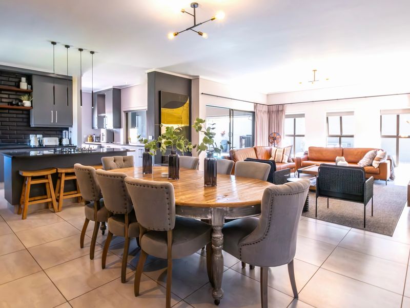 Spacious open-plan living area featuring a modern kitchen with island, dining space, and lounge area with large sliding doors leading to the outdoors.