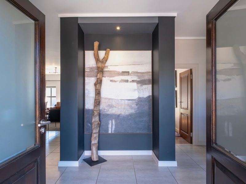 Welcoming entrance hall featuring tiled flooring, double glass panel doors, and a modern recessed feature wall with integrated spotlighting.