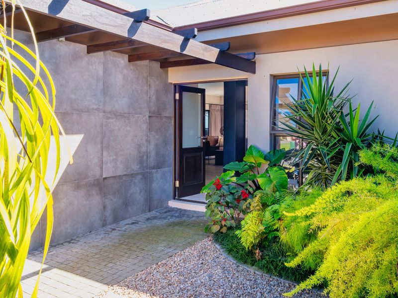 Modern front entrance featuring a timber pergola, large format feature wall tiles, and a neatly landscaped garden with a paved walkway.