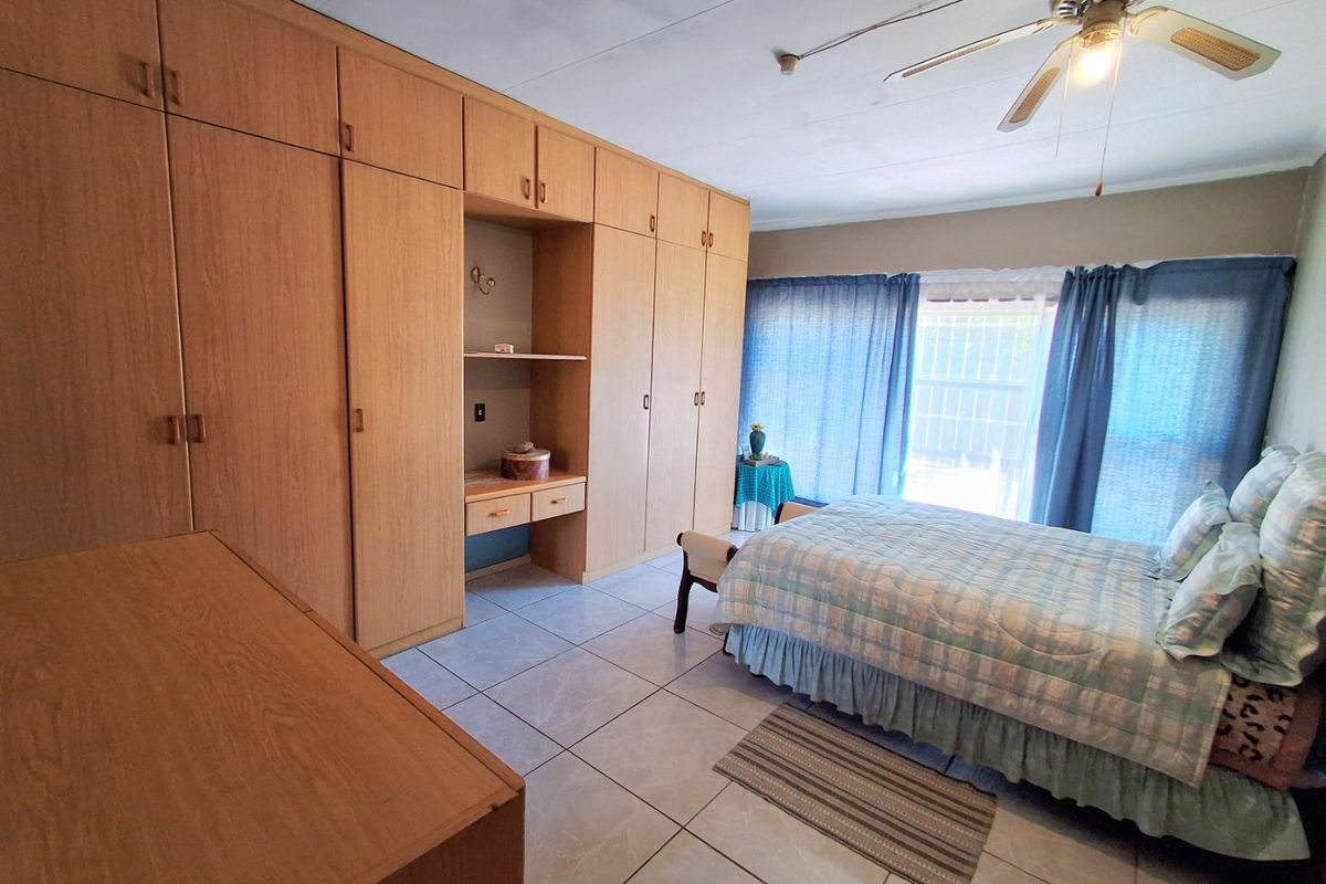 A bedroom featuring extensive built-in wooden cabinetry, tiled flooring, and a ceiling fan, offering ample storage space.