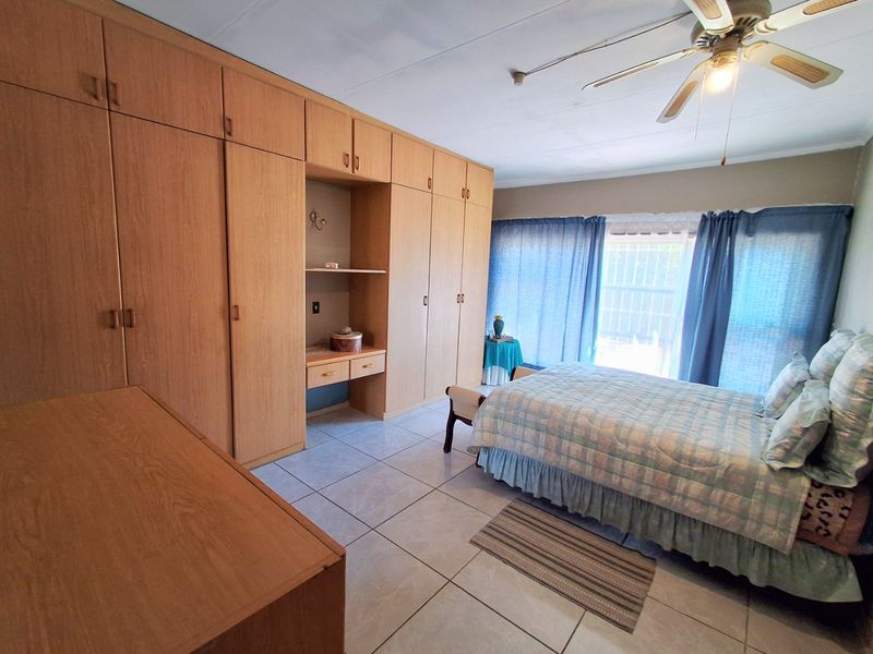 A bedroom featuring extensive built-in wooden cabinetry, tiled flooring, and a ceiling fan, offering ample storage space.