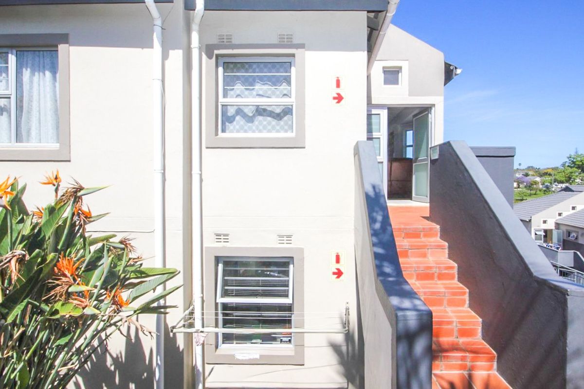 Exterior view of an apartment building featuring an external staircase with tiled steps and access to an upper-level entrance.