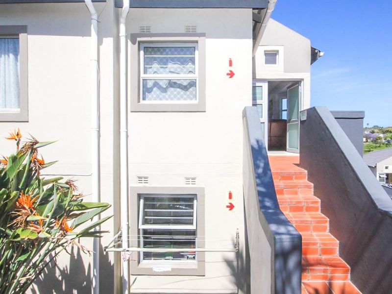 Exterior view of an apartment building featuring an external staircase with tiled steps and access to an upper-level entrance.