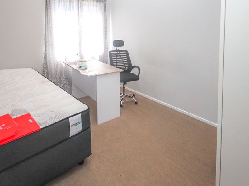 A functional bedroom featuring neutral wall finishes, carpet flooring, and a built-in wardrobe, offering a versatile space for rest or study.