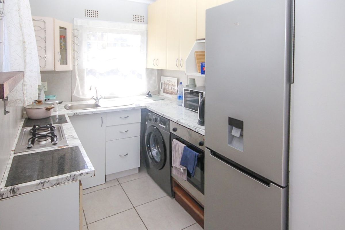 Compact kitchen featuring built-in cabinetry, laminate countertops, a gas hob, and integrated oven, with tiled flooring and functional layout.