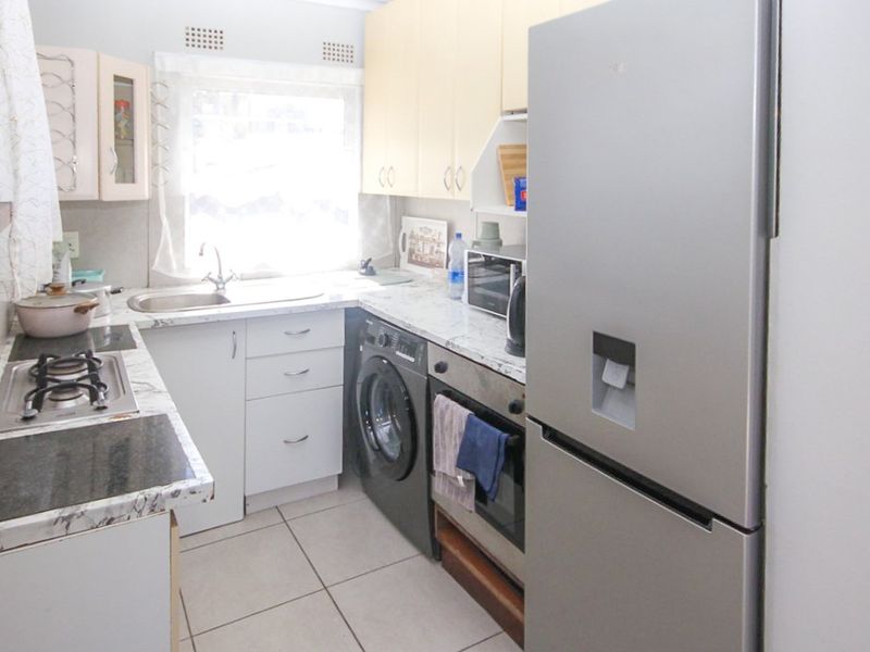 Compact kitchen featuring built-in cabinetry, laminate countertops, a gas hob, and integrated oven, with tiled flooring and functional layout.