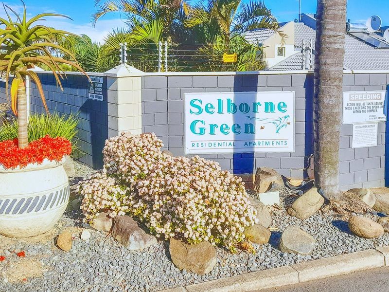 The entrance signage and boundary wall for Selborne Green residential apartments, featuring secure electric fencing and landscaped garden beds.