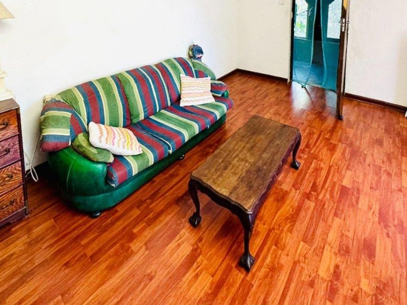 A living room area featuring warm-toned laminate flooring and neutral wall finishes, providing a functional space for relaxation.