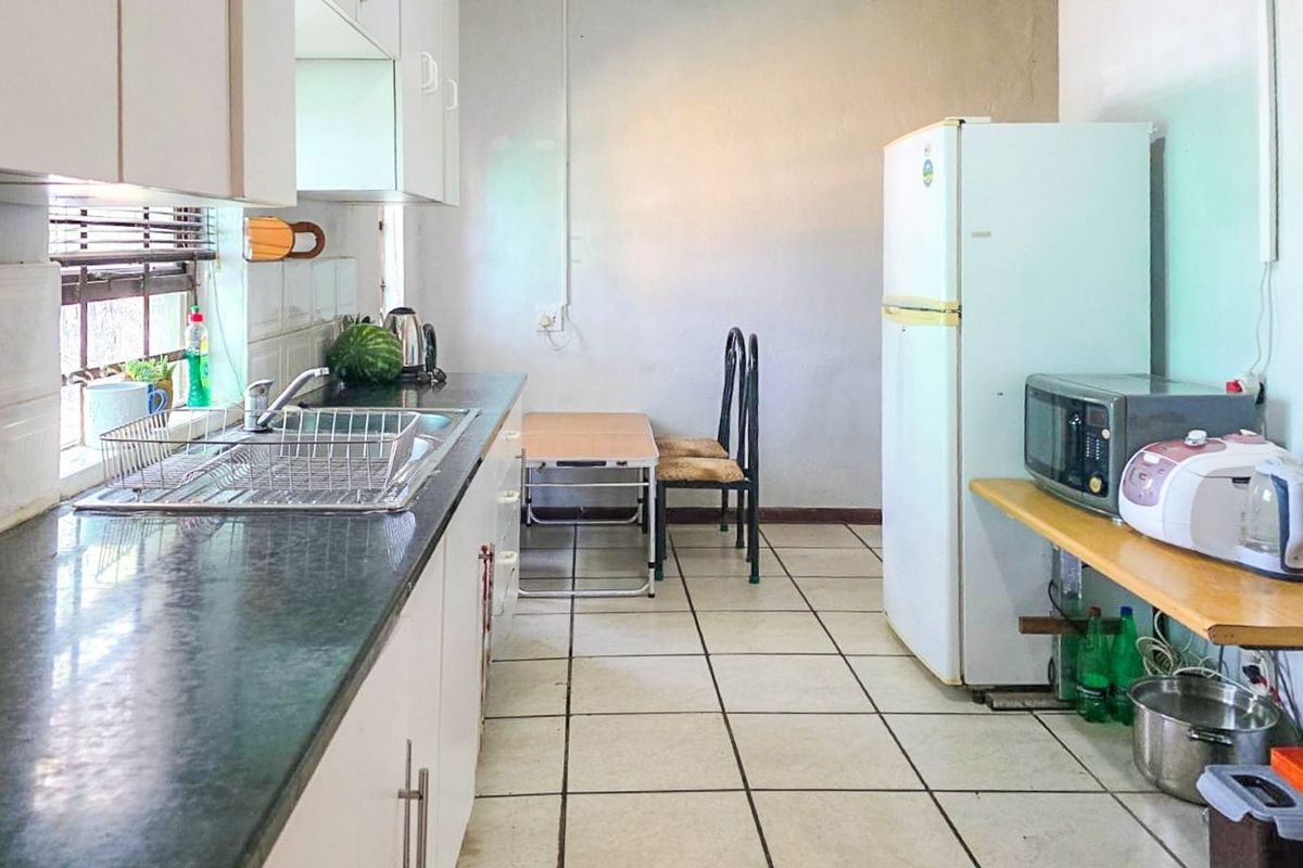 A functional kitchen featuring laminate countertops, built-in cabinetry, and tiled flooring, offering a practical layout with potential for modern updates.