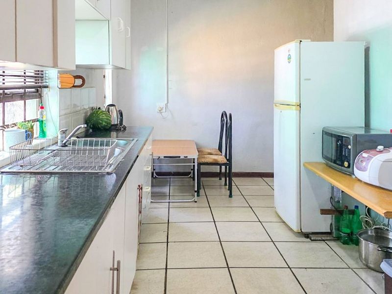 A functional kitchen featuring laminate countertops, built-in cabinetry, and tiled flooring, offering a practical layout with potential for modern updates.