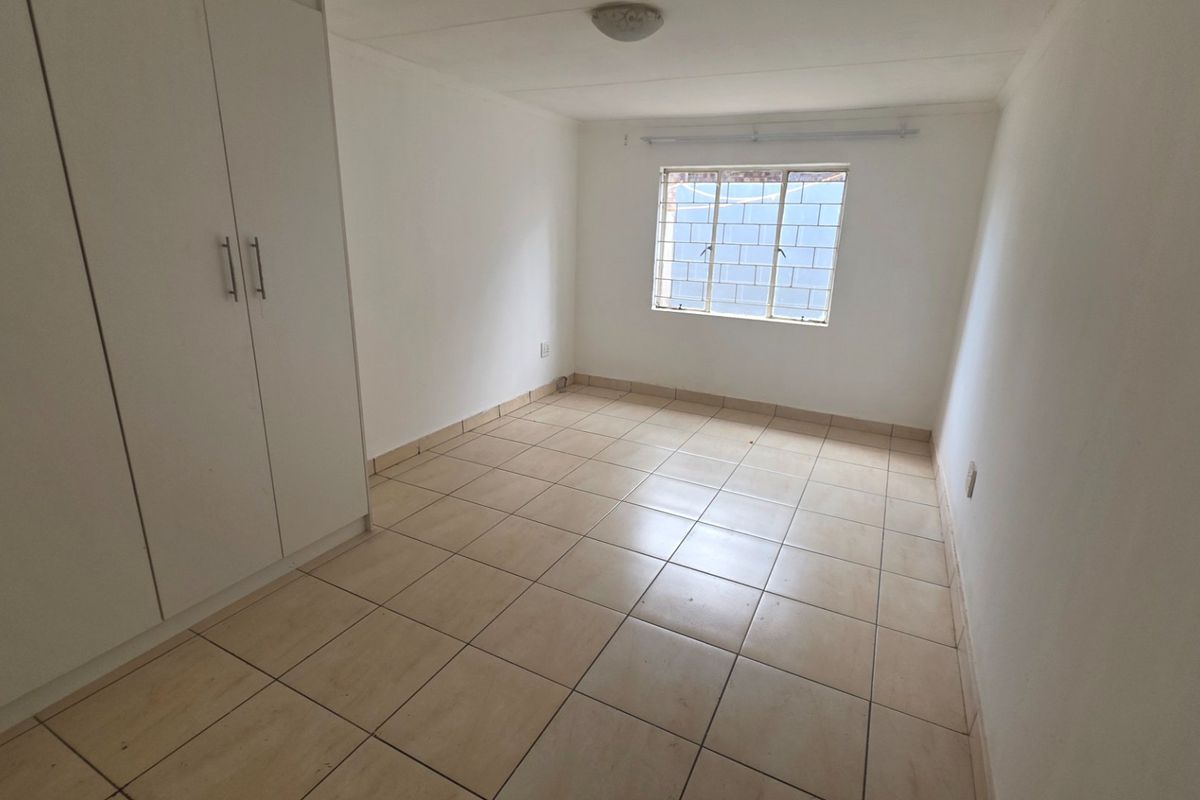 A clean, empty bedroom featuring neutral tiled flooring and built-in cupboards, providing a versatile space ready for personalization.