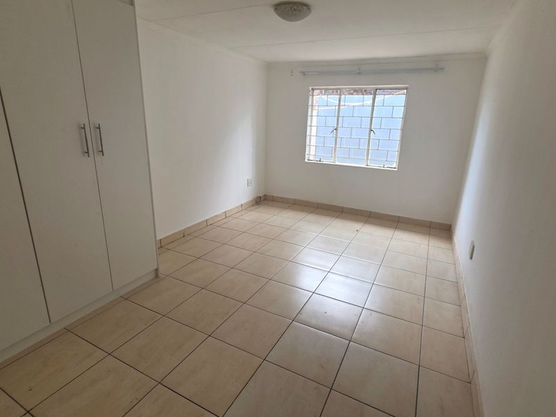 A clean, empty bedroom featuring neutral tiled flooring and built-in cupboards, providing a versatile space ready for personalization.