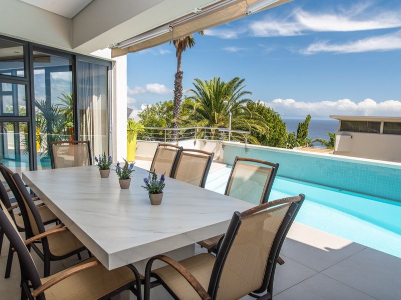 Covered patio featuring tiled flooring, a retractable awning, and direct access to a swimming pool with scenic ocean views.