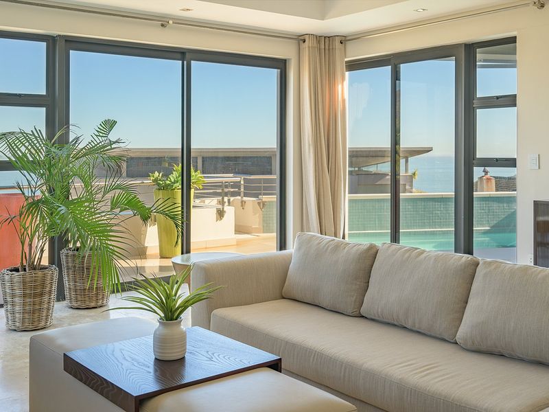 Bright living room featuring expansive sliding glass doors that open onto a terrace with pool and ocean views.