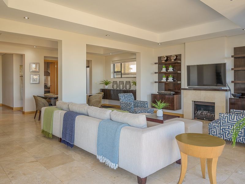 Spacious open-plan living area featuring stone tile flooring, a built-in fireplace with stone surround, and integrated shelving units under a coved ceiling.