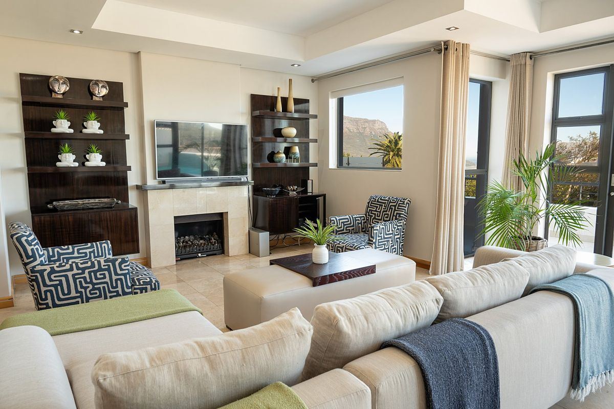 A well-maintained living room featuring a built-in fireplace with stone surround, custom dark wood shelving, tiled floors, and large windows with natural light.