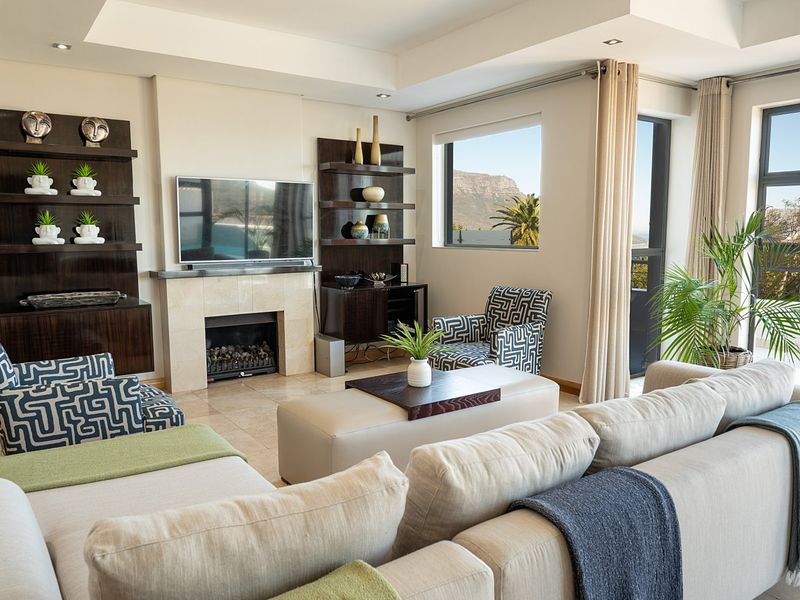 A well-maintained living room featuring a built-in fireplace with stone surround, custom dark wood shelving, tiled floors, and large windows with natural light.