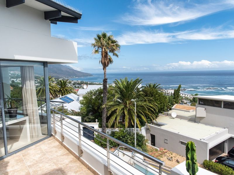 A modern balcony featuring tiled flooring and a stainless steel balustrade, offering expansive coastal and ocean views.