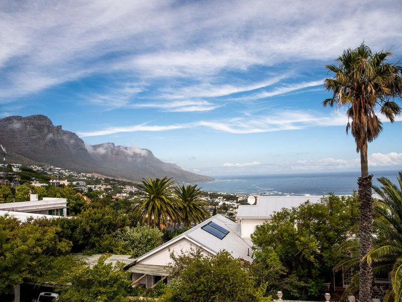Elevated coastal view featuring mountain scenery, ocean horizon, and surrounding residential landscape with visible solar water heating infrastructure.