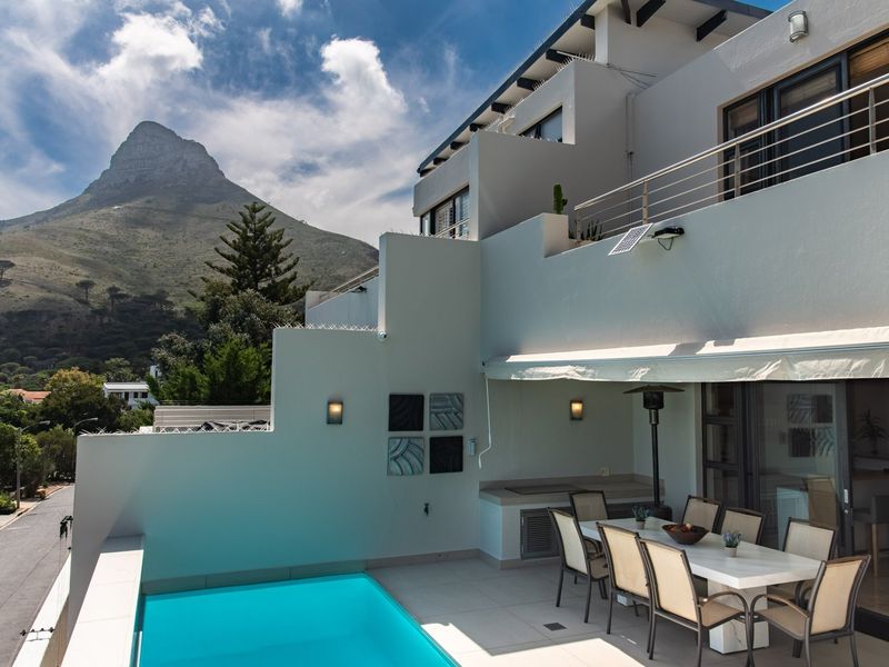 Spacious elevated patio featuring a private swimming pool, built-in braai area, and retractable awning, offering stunning mountain views.