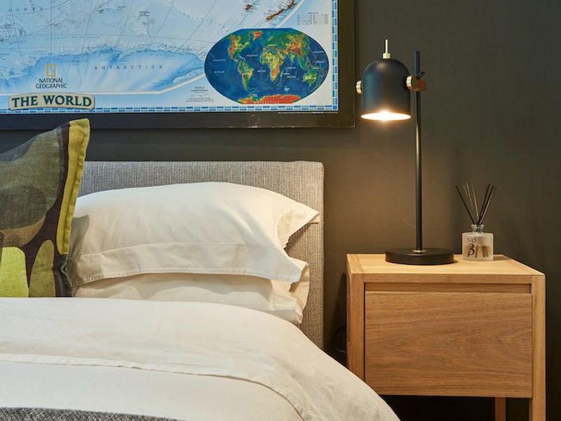 A well-appointed bedroom featuring dark accent walls and warm hardwood flooring, creating a cozy and modern atmosphere.
