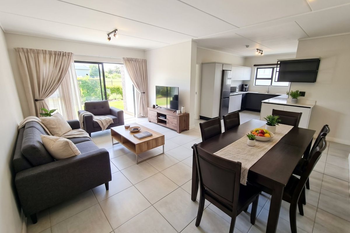 Spacious open-plan living, dining, and kitchen area featuring neutral tiled flooring, modern cabinetry, and large sliding doors leading to the outdoor space.