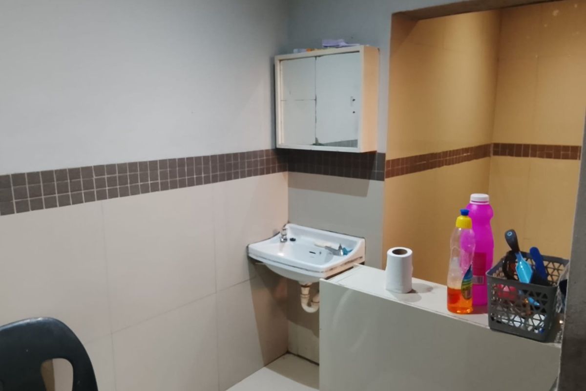 A functional bathroom space featuring a wall-mounted basin, tiled splashback, and a built-in medicine cabinet, requiring cosmetic updates to improve its overall condition.