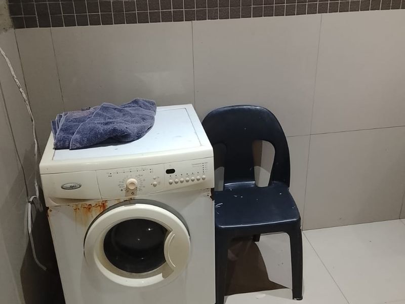 A functional laundry area featuring tiled walls and flooring, providing a dedicated space for washing appliances.