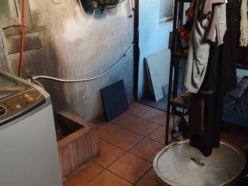 A functional laundry area featuring tiled flooring and a wall-mounted electric water heater, requiring cosmetic updates to improve the overall condition.