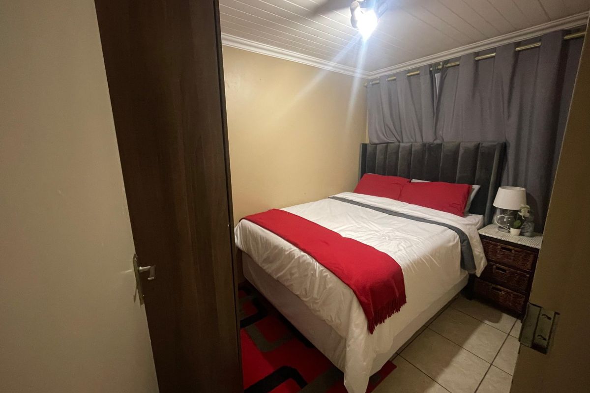 A compact bedroom featuring tiled flooring, a tongue and groove ceiling, and a ceiling fan.