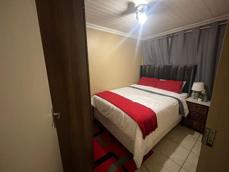 A compact bedroom featuring tiled flooring, a tongue and groove ceiling, and a ceiling fan.