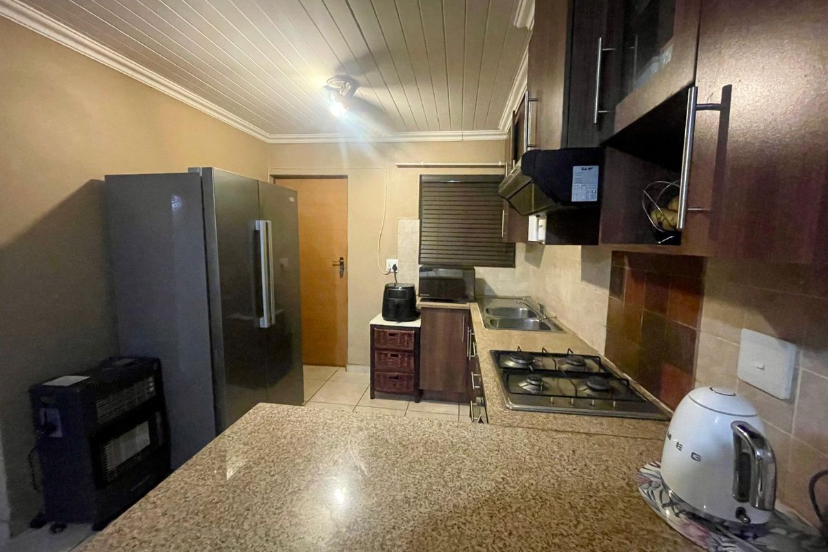 Functional kitchen featuring granite countertops, built-in cabinetry, a gas hob with extractor fan, and a double sink, finished with a tongue and groove ceiling.