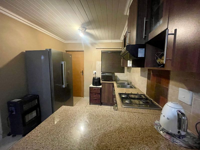 Functional kitchen featuring granite countertops, built-in cabinetry, a gas hob with extractor fan, and a double sink, finished with a tongue and groove ceiling.