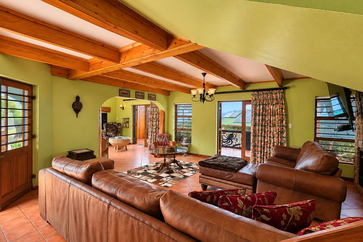 Spacious living room featuring exposed timber beams, terracotta flooring, and a stone-clad fireplace, with direct access to an outdoor balcony area.