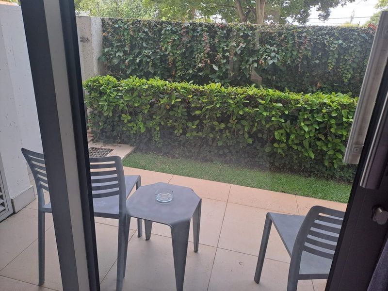 A private ground-floor patio featuring tiled flooring and a well-maintained hedged garden boundary, offering a peaceful outdoor space.