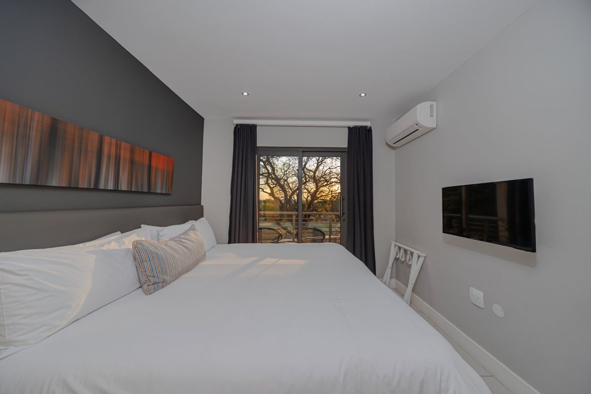 A well-maintained bedroom featuring recessed lighting, a wall-mounted air conditioning unit, and sliding glass doors that open to an outdoor view.