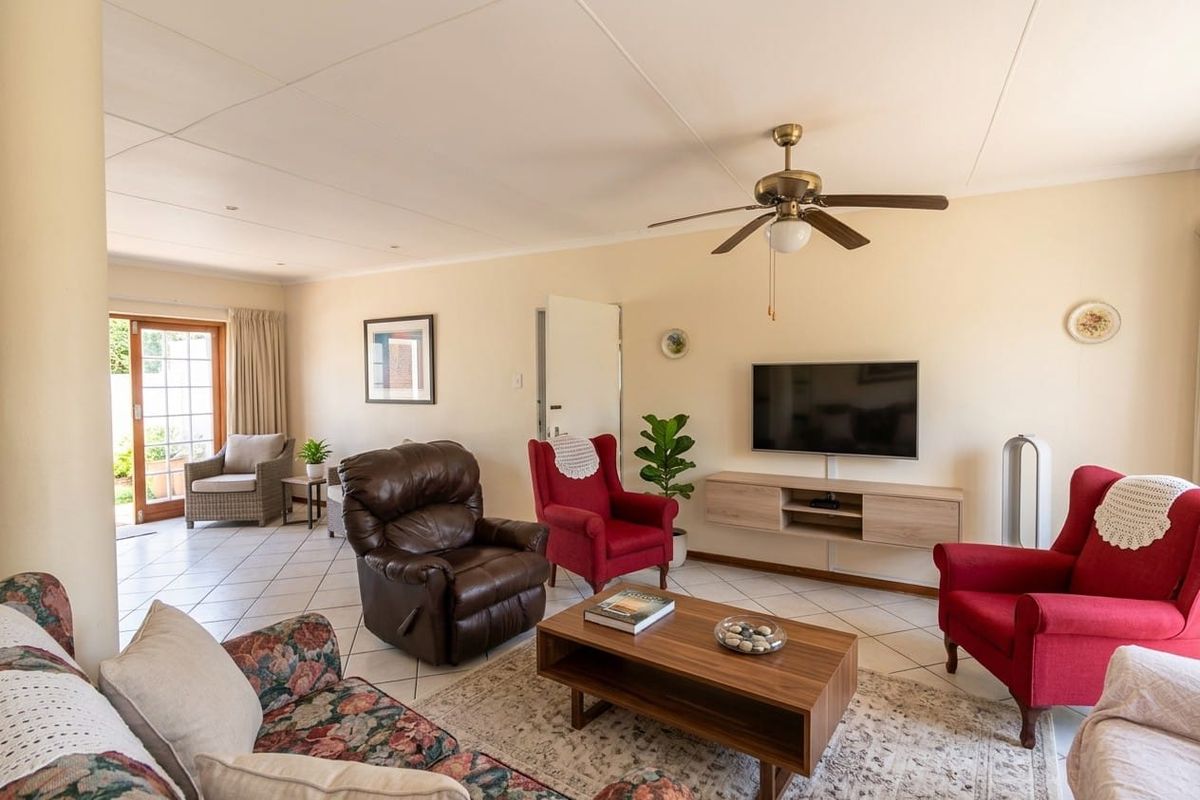 Spacious living room featuring tiled flooring, a ceiling fan, and direct access to the outdoor patio area through sliding glass doors.