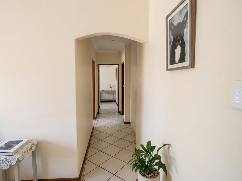 A clean, neutral-toned hallway featuring tiled flooring and an arched transition leading to further living spaces.