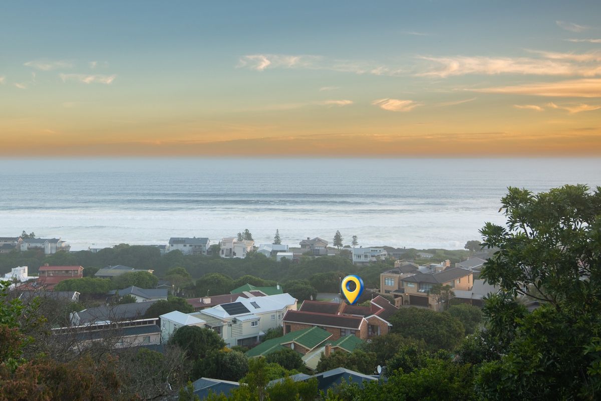 An elevated aerial view overlooking a coastal residential neighborhood with a clear view of the ocean horizon.