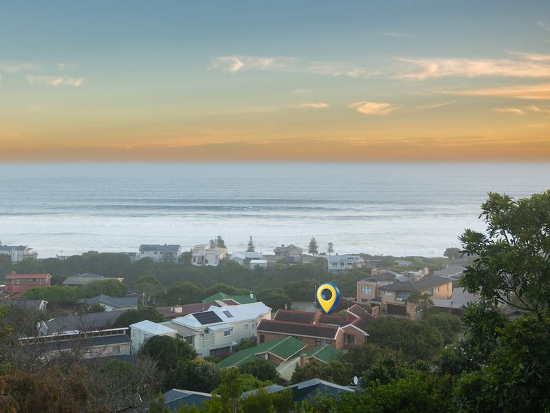 An elevated aerial view overlooking a coastal residential neighborhood with a clear view of the ocean horizon.