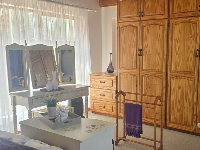 A bedroom featuring extensive built-in wooden cabinetry and large windows with sheer curtains, providing ample storage and natural light.