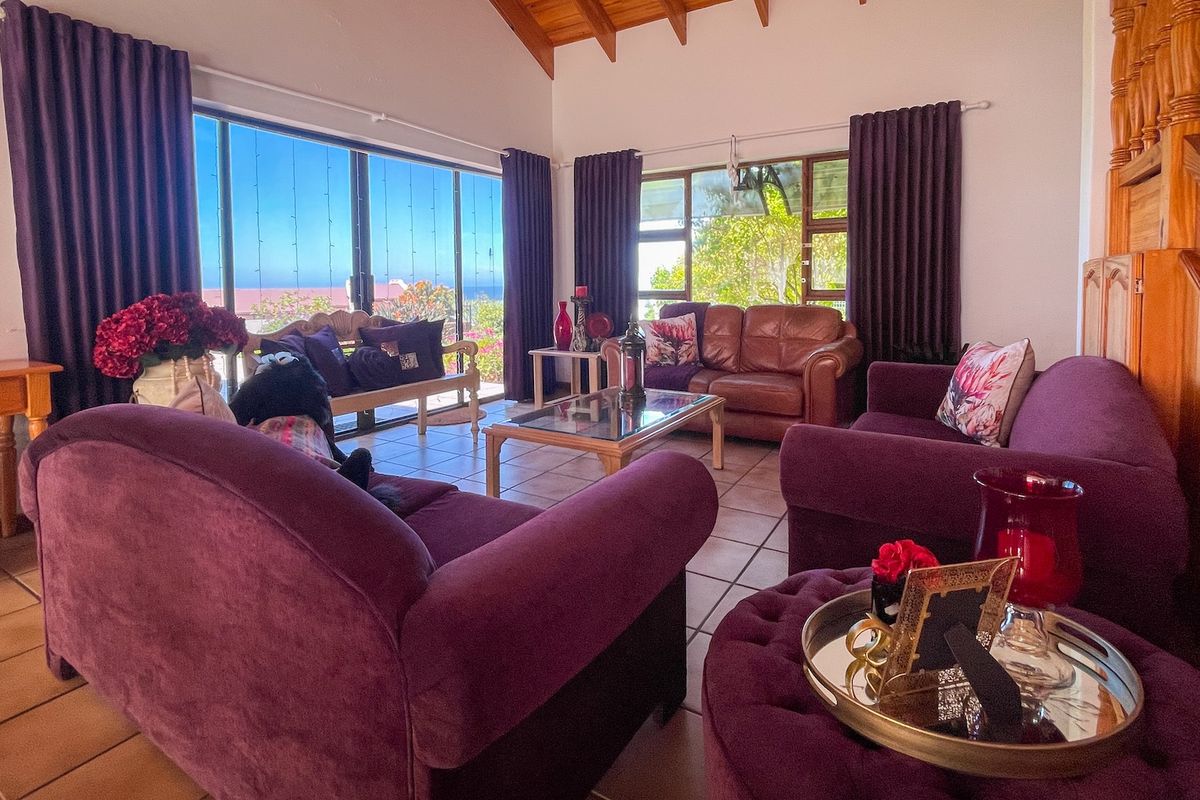 Spacious living room featuring a vaulted timber ceiling with exposed beams, tiled flooring, and large sliding glass doors offering natural light and outdoor views.