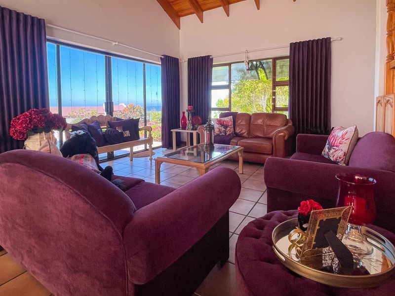 Spacious living room featuring a vaulted timber ceiling with exposed beams, tiled flooring, and large sliding glass doors offering natural light and outdoor views.